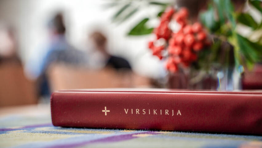 Virsikirja ja pihlajanoksa maljakossa pöydälle aseteltuna.