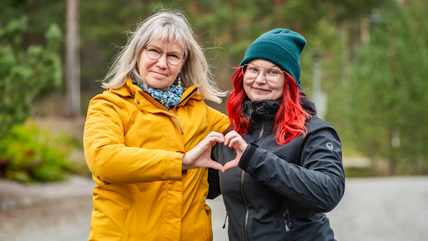 Kaksi nuorisotyöntekijää muodostaa sormillaan sydämen.
