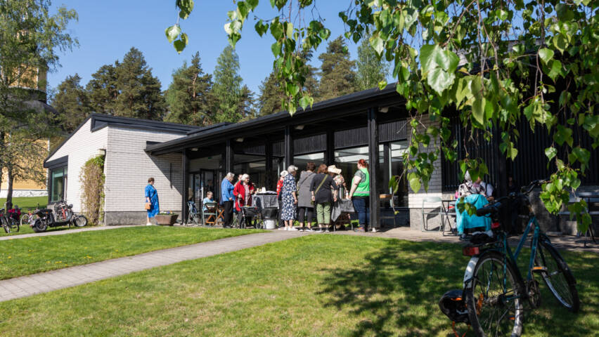 Ihmisiä Kirkonmäen seurakuntatalon pihalla kesällä.