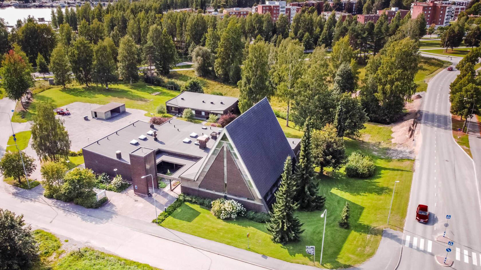 Ilmakuva tummasta kirkkotilasta puuston ja asutuksen keskellä
