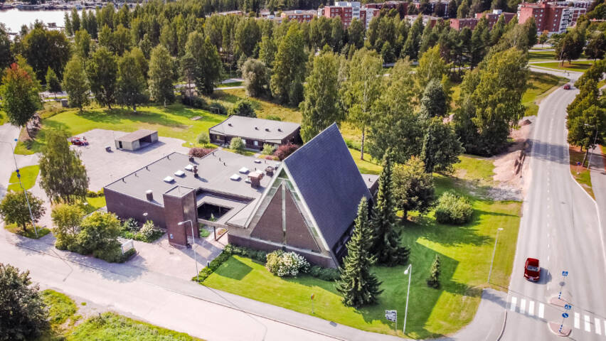Ilmakuva tummasta kirkkotilasta puuston ja asutuksen keskellä