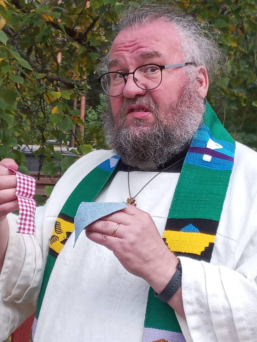 Pappi Olli J. Vuoristo-Watia pitelee kangastilkkuja hämmästyneenä käsissään.